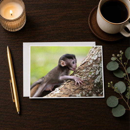 a small monkey climbing a tree, with a candle and a cup of coffee on a wooden surface.