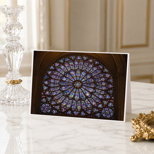 A framed photograph of a stained glass window is displayed on a marble countertop, with a crystal candlestick and a gold-colored decorative piece in the background.