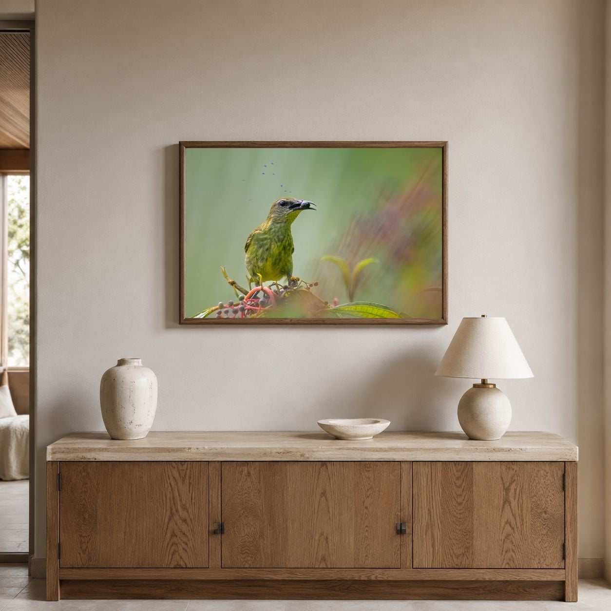 Framed artwork of a bird on a wall above a wooden cabinet with decorative items.