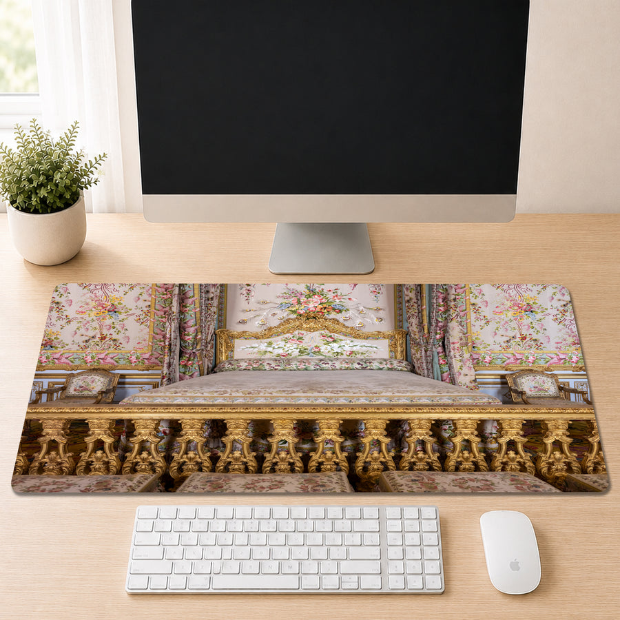 A computer desk with a large monitor, keyboard, and mouse, along with a decorative floral pattern on the mouse pad.