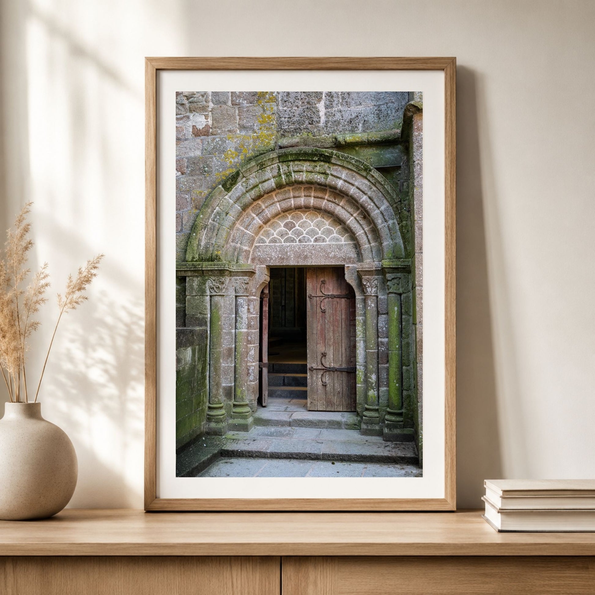 Framed Mont Saint-Michel Abbey doorway photography print displayed on a wood cabinet in a warm neutral interior