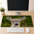 a computer desk with a monitor, keyboard, and mouse. The monitor is turned off, and the desk has a mouse and keyboard placed on it. There is also a mouse pad with a deer image on it.
