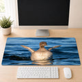 Baby Common Loon desk mat featuring original New Hampshire wildlife photography by Linda Nee, shown beneath a white keyboard on a light wood desk.