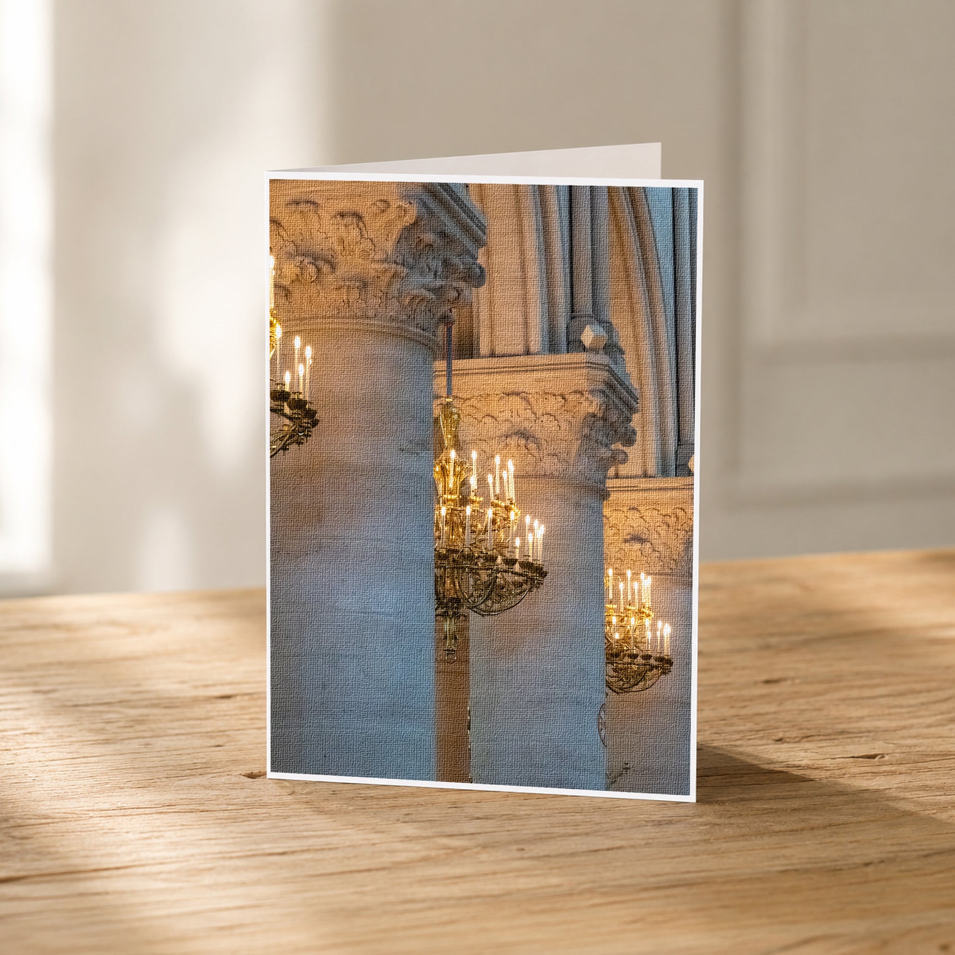 A photograph of ornate stone columns with a large chandelier hanging from the center, displayed on a wooden surface.