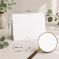 a blank white card placed on a table, with a magnifying glass nearby. The card is 5 inches wide and 7 inches tall, as indicated by the text 
