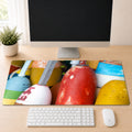 Stack of weathered, brightly painted lobster buoys in red, yellow, blue, and white, shown as a desk mat design on a wood desk