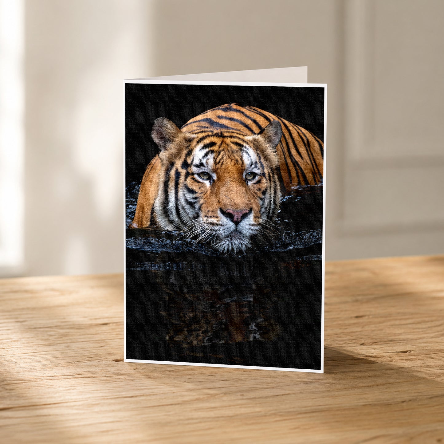 A close-up photograph of a tiger resting in water, with its reflection visible in the water.