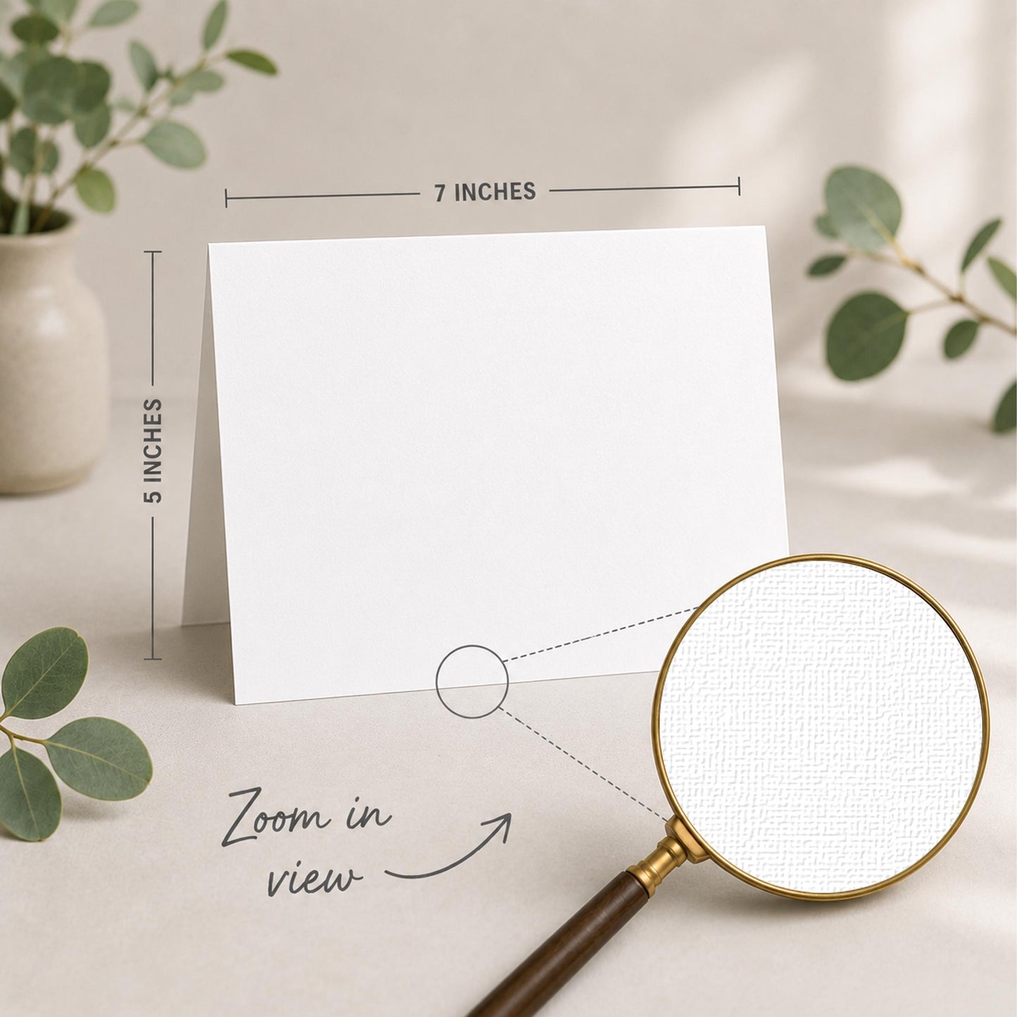 a blank white card placed on a table, with a magnifying glass nearby. The card is 5 inches wide and 7 inches tall, as indicated by the text "5 INCHES" and "7 INCHES" above and below the card, respectively. The magnifying glass is also shown in the image, with the text "Zoom in view" written below it.