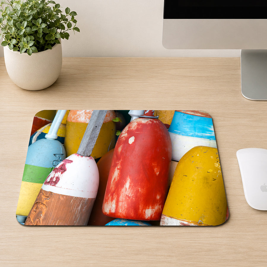 Stack of weathered red, yellow, and blue lobster buoys in close-up, printed on a mouse pad