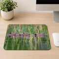 Three beavers swimming in a line through green marsh grass on calm water, printed on a mouse pad