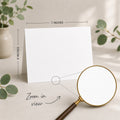 a blank white card placed on a table, with a magnifying glass nearby. The card is 5 inches wide and 7 inches tall, as indicated by the text 
