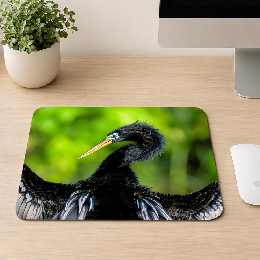 Anhinga bird with bright blue eye ring, orange bill, and dark spread feathers against a green background, printed on a mouse pad