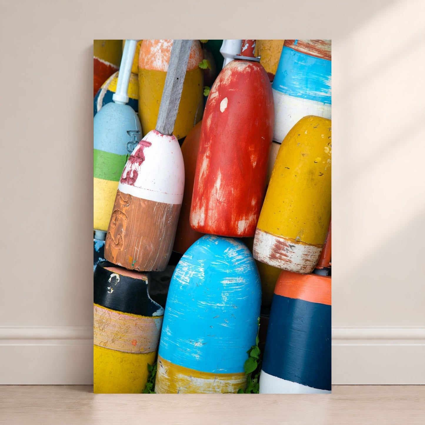 Colorful lobster buoys in red, yellow, blue, white, and orange stacked together with weathered paint and coastal texture