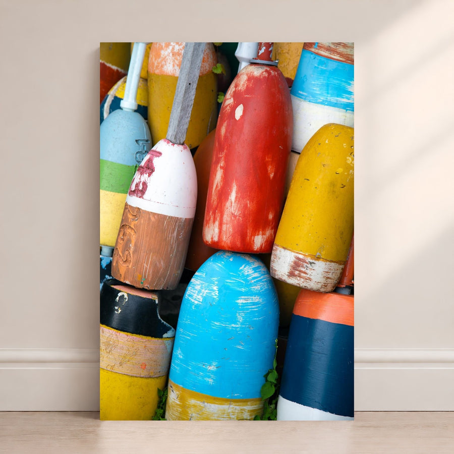 Colorful lobster buoys in red, yellow, blue, white, and orange stacked together with weathered paint and coastal texture