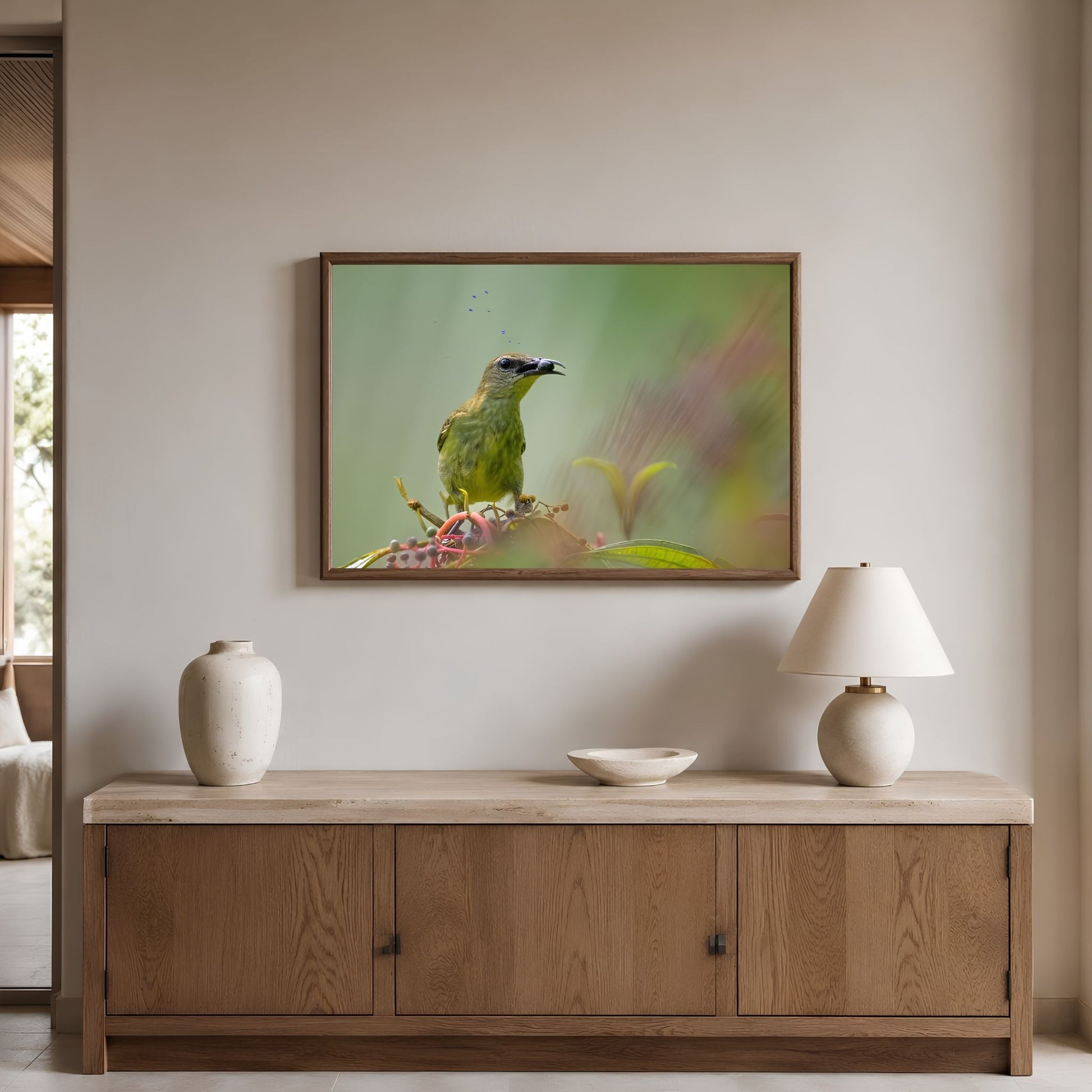 Framed artwork of a green bird on a wall above a wooden cabinet with decorative items.