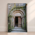 Mont Saint-Michel Abbey doorway photography print leaning against a wall, featuring an ancient stone arch and wooden door
