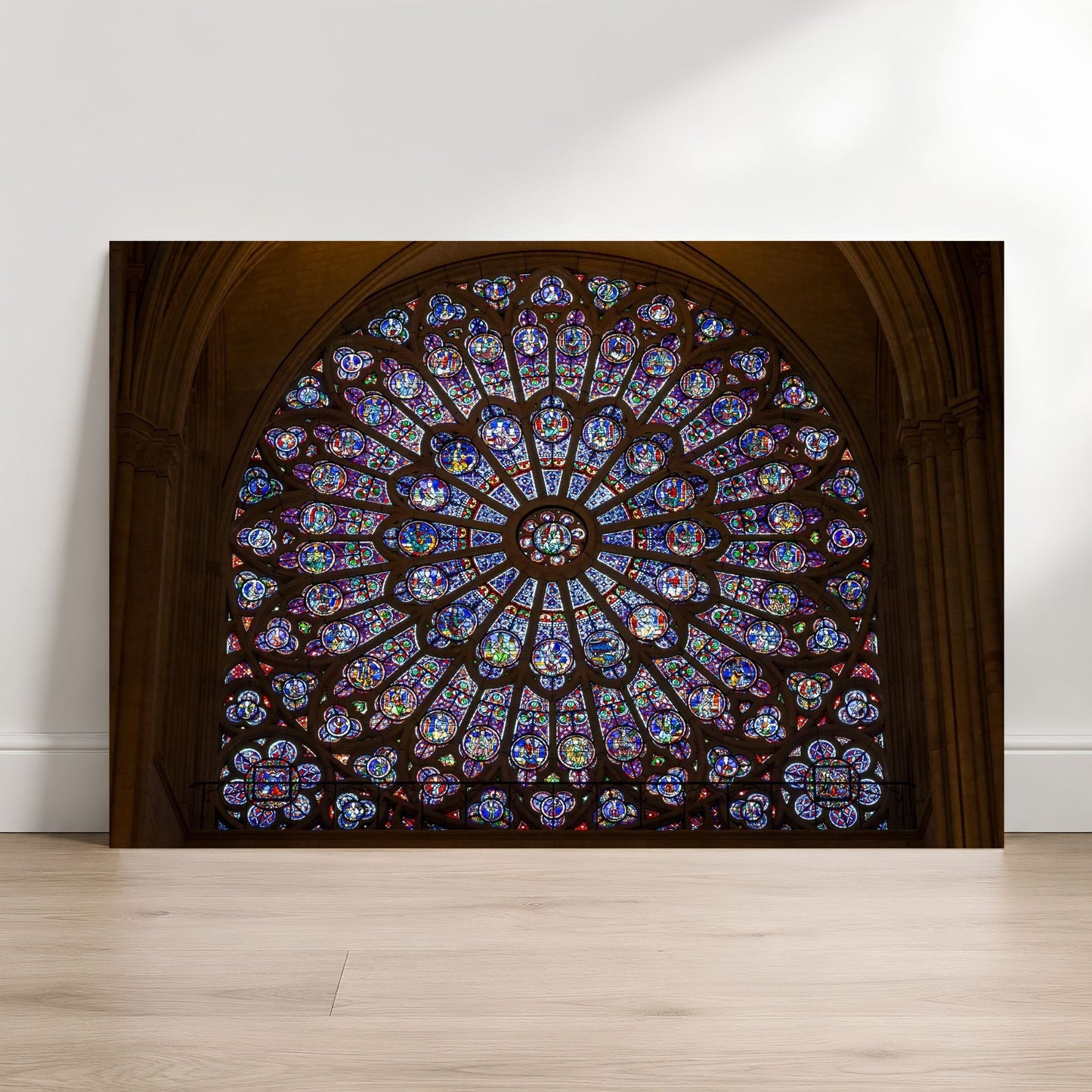Notre-Dame rose window fine art photography print leaning against a white wall on a light wood floor.