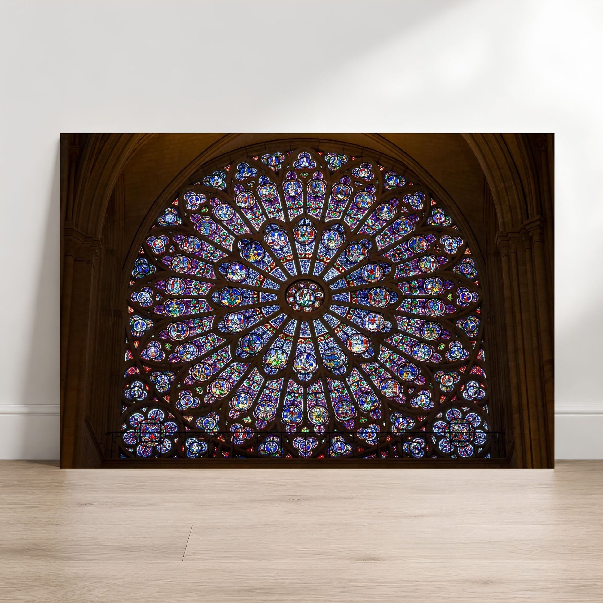 Notre-Dame rose window fine art photography print leaning against a white wall on a light wood floor.