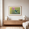 Framed artwork of a hummingbird and flower above a wooden console table in a living room.