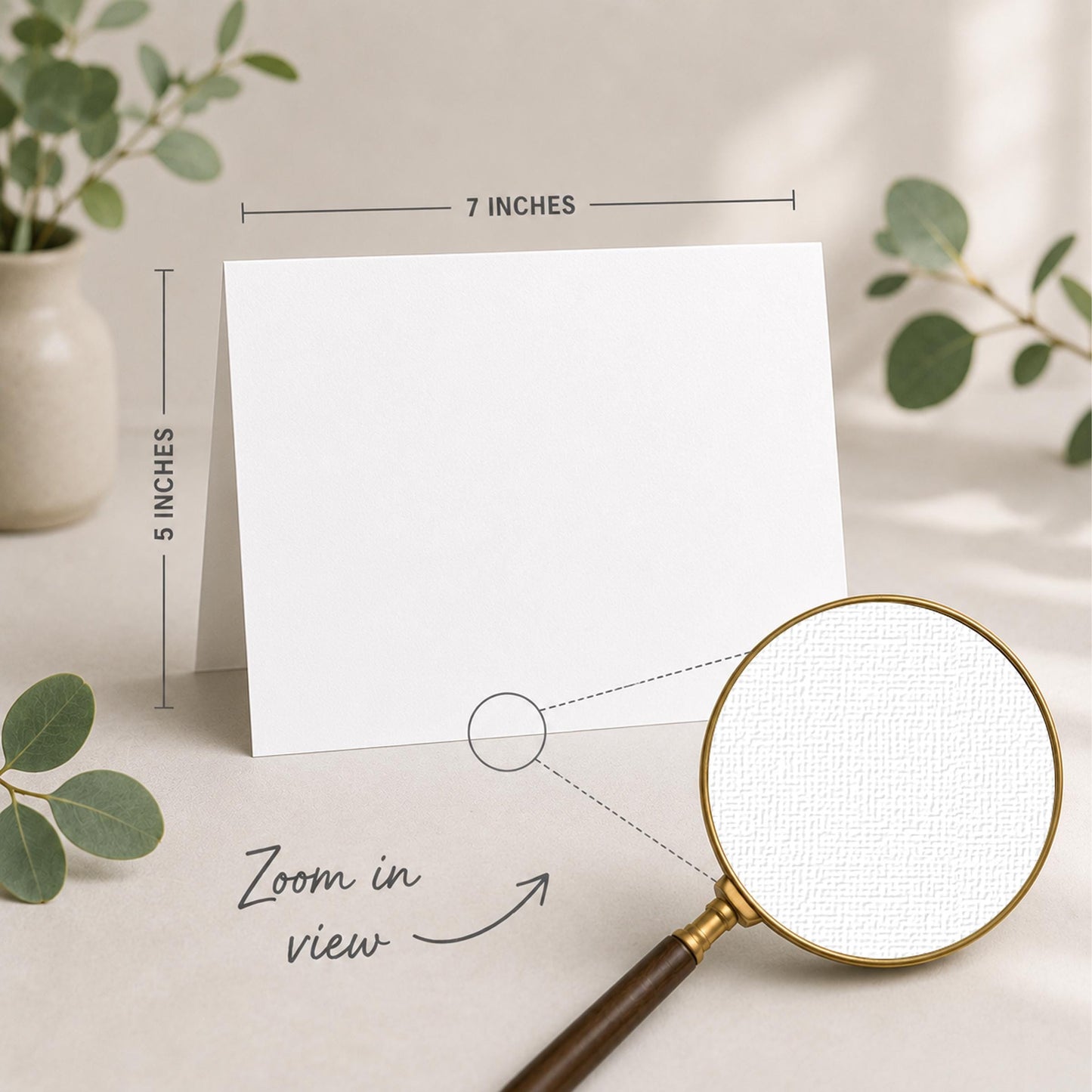 a blank white card placed on a table, with a magnifying glass nearby. The card is 5 inches wide and 7 inches tall, as indicated by the text "5 INCHES" and "7 INCHES" above and below the card, respectively. The magnifying glass is also shown in the image, with the text "Zoom in view" written below it.