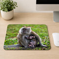 Long-tailed Macaque mother cradling her baby against her chest on the grass, printed on a mouse pad