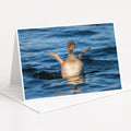 A duck swimming in the water with its wings spread wide.