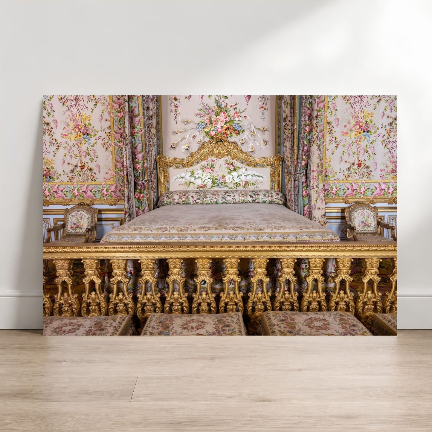 an ornate, gilded bed with floral patterns and a white headboard, situated in a room with a white wall and wooden floor.