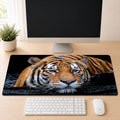Malayan tiger swimming through dark water with a direct gaze, shown as a desk mat design on a wood desk