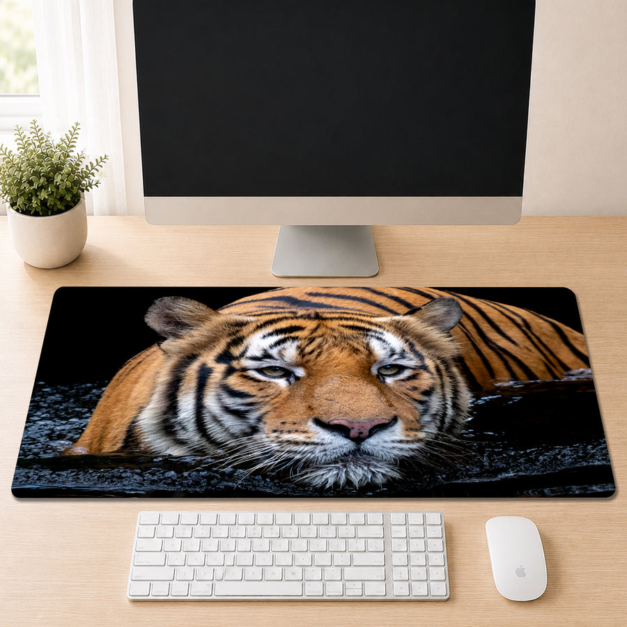 Malayan tiger swimming through dark water with a direct gaze, shown as a desk mat design on a wood desk