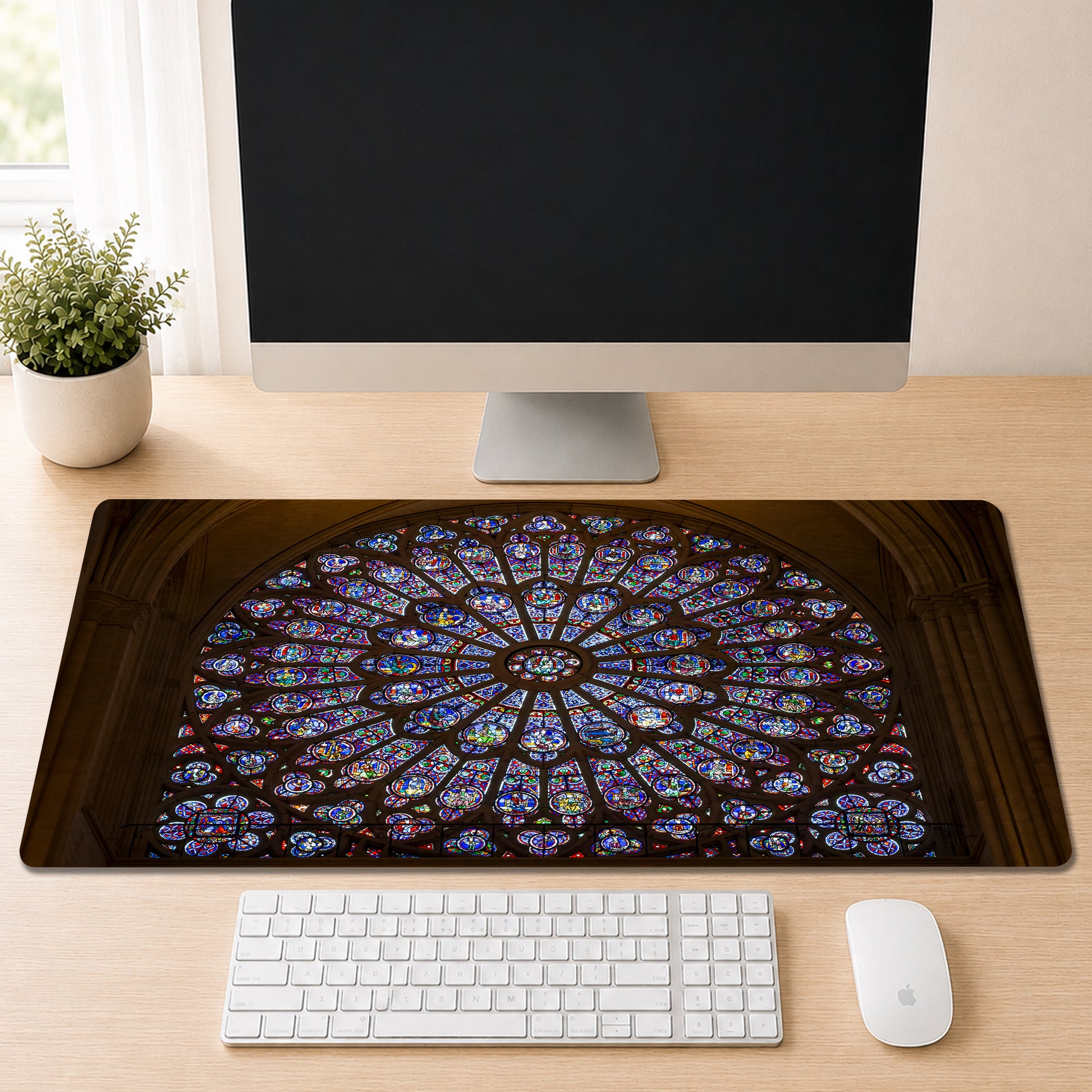 Notre-Dame Cathedral's circular stained glass rose window in jewel-toned blue, red, and gold, shown as a desk mat design on a wood desk