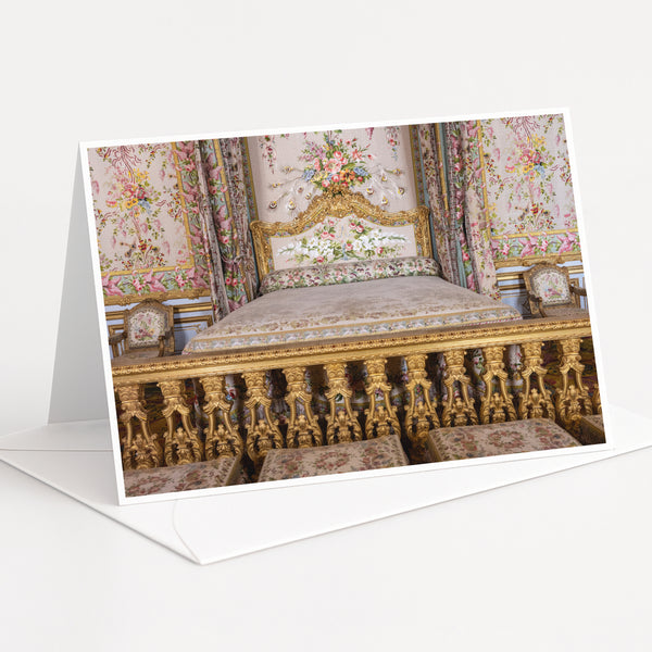 an ornate, gilded bed with intricate floral patterns and gold accents, set against a backdrop of a wall with a floral tapestry.