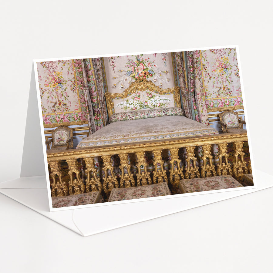 an ornate, gilded bed with intricate floral patterns and gold accents, set against a backdrop of a wall with a floral tapestry.