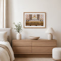 a serene and elegant bedroom setting, featuring a wooden dresser with a bowl on top, a framed picture of a palace, a lamp, and a plant.