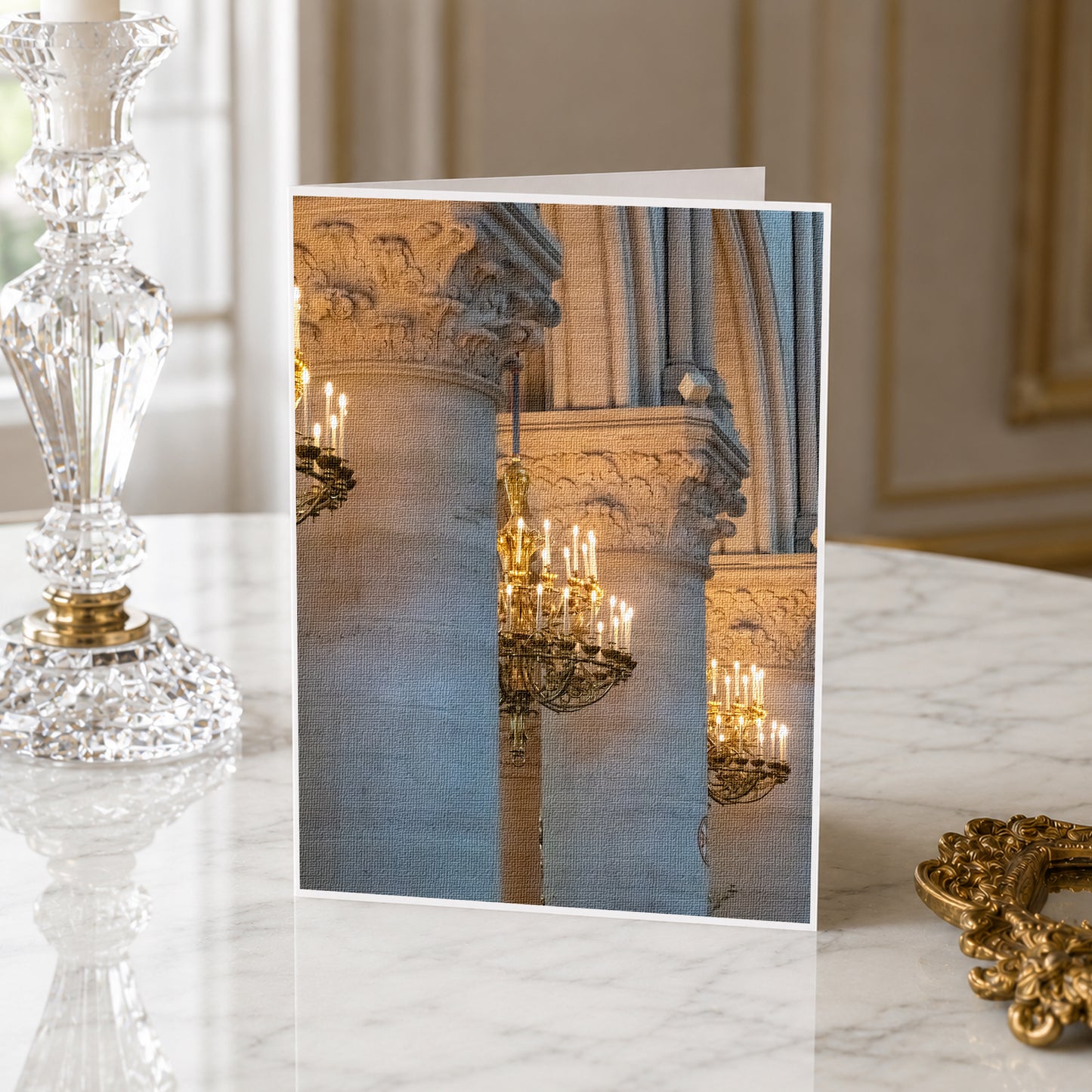 a marble table with a crystal candlestick and a framed photograph of ornate columns with chandeliers.