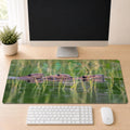 Beaver family desk mat featuring original New Hampshire wildlife photography by Linda Nee, shown beneath a white keyboard on a light wood desk.