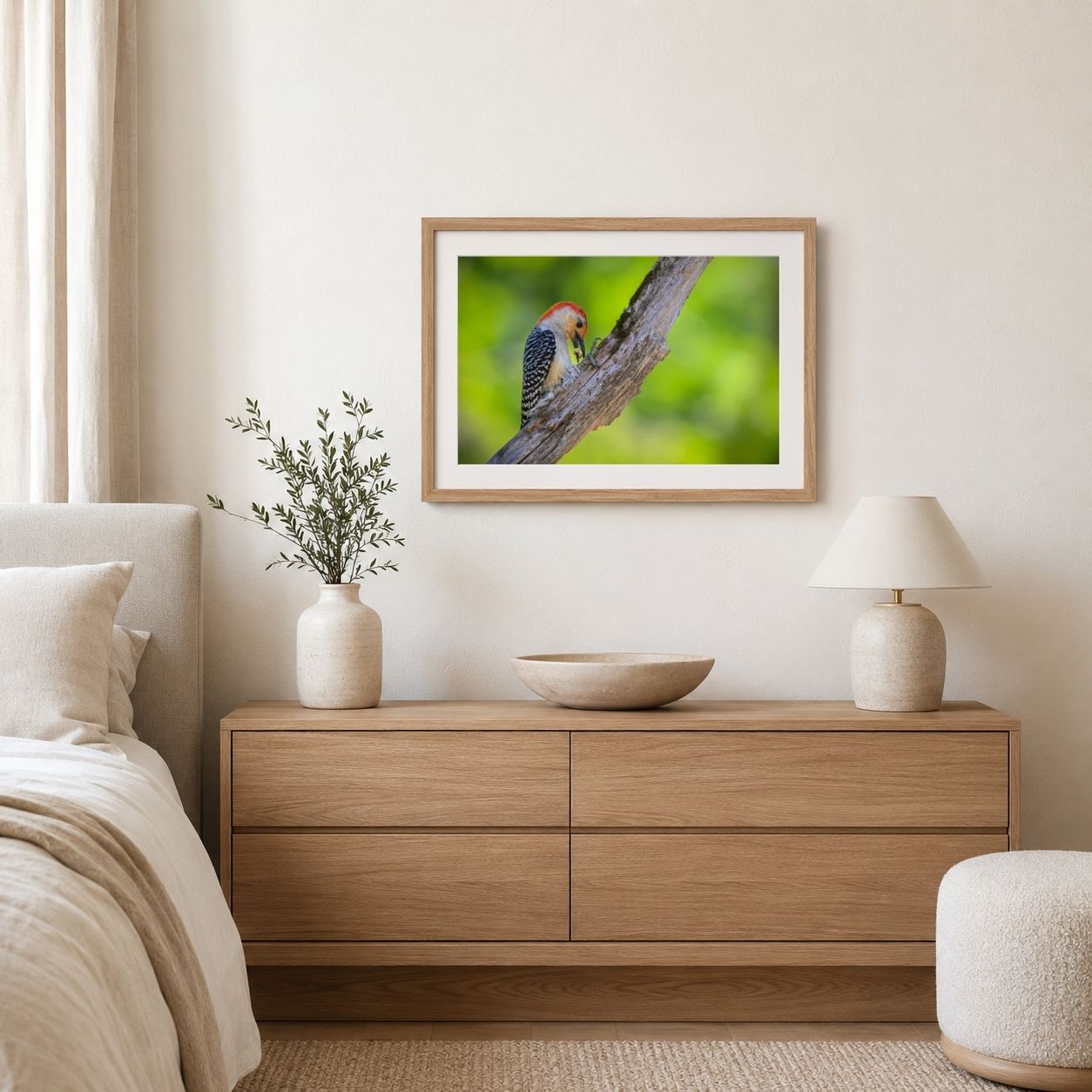 Framed picture of a bird on a branch above a wooden dresser in a bedroom.